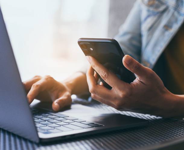 a person using a laptop and a phone