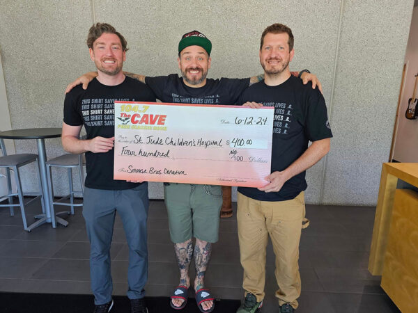 Three men holding large donation check
