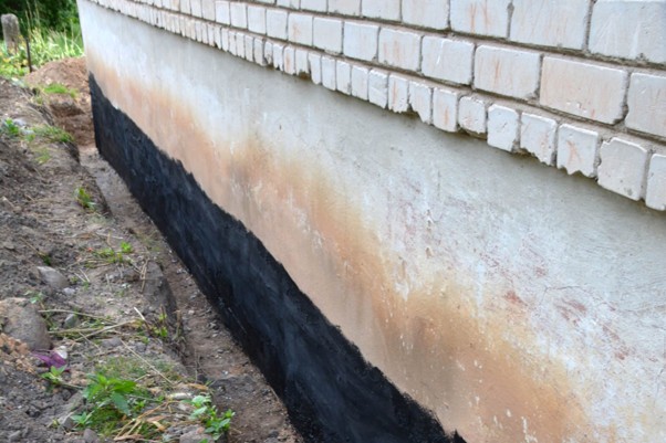 Foundation wall with drainage trench visible